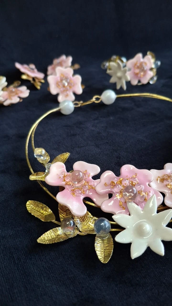 Detalhe de flores rosadas e claras em uma peça de joalheria